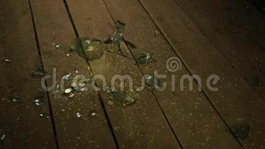 一个白人男人的手从地板上拿起一张黄色小米的特写。 在碎玻璃旁边。
